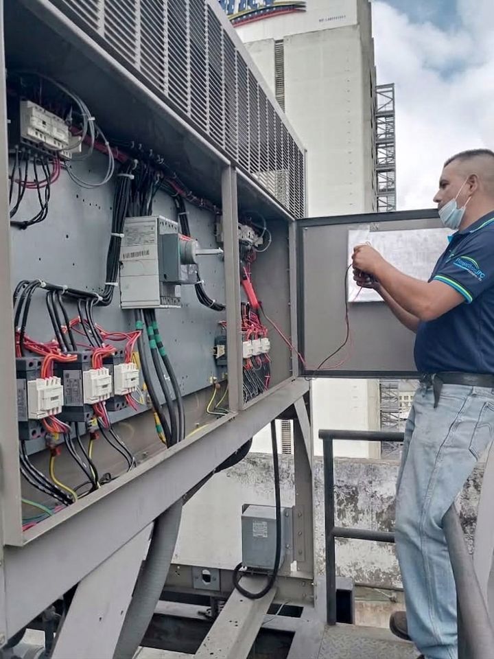 Técnico de Proyectos JPC revisando el cableado del tablero eléctrico de un equipo de aire acondicionado en una azotea.